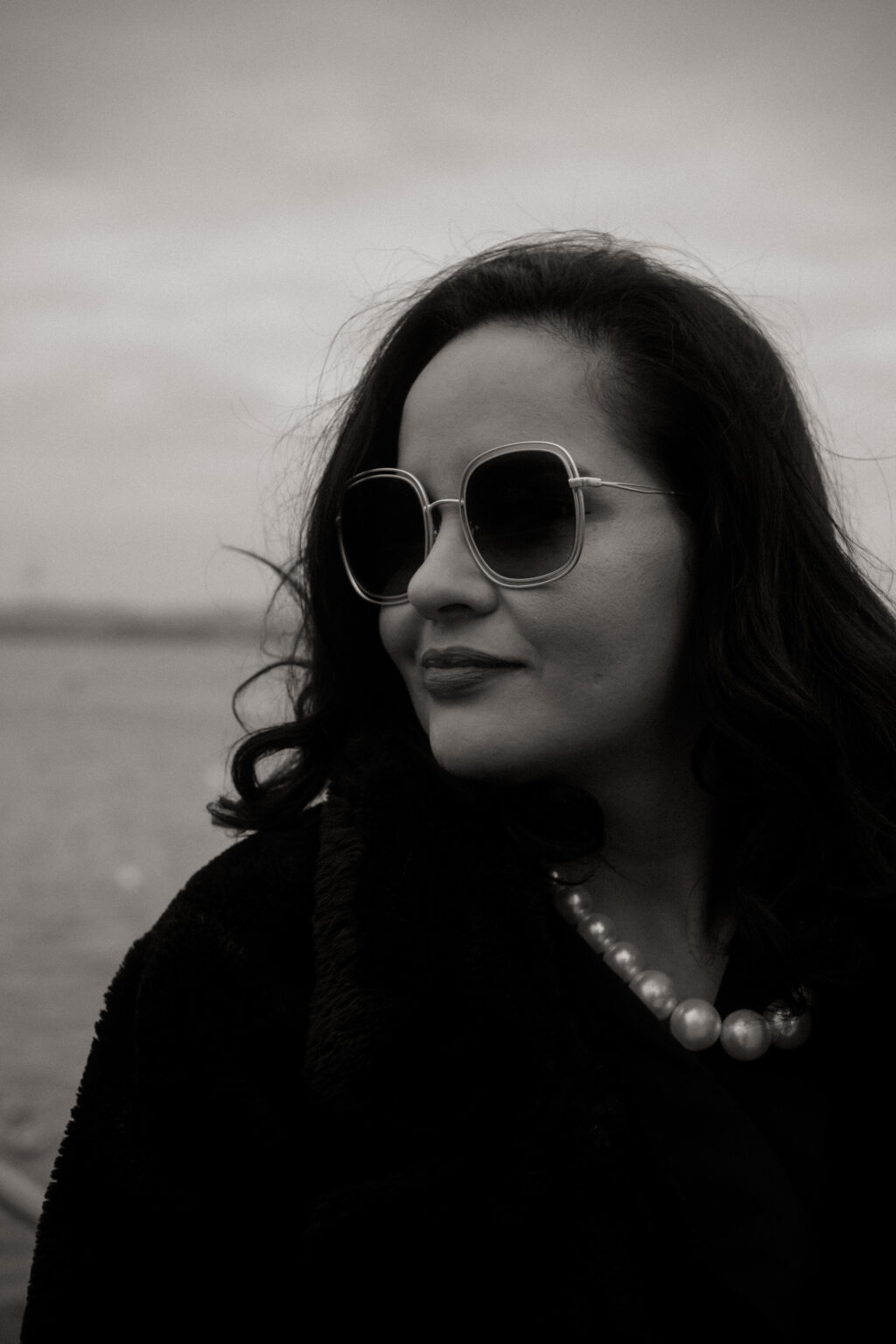 Juliem Rechmann mit Sonnenbrille und Perlenkette am See